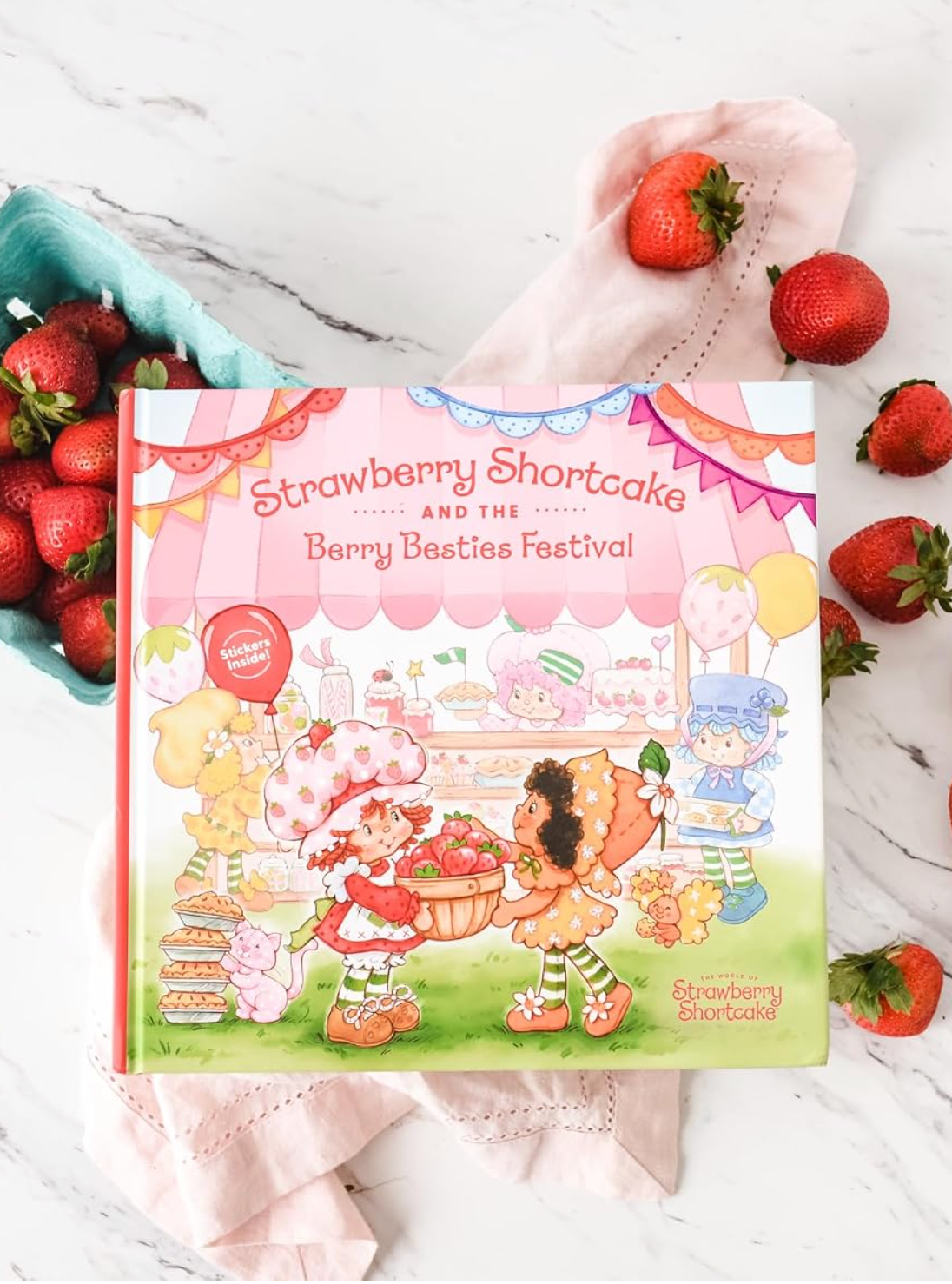 Strawberry Shortcake and the Berry Besties Festival beside fresh strawberries
